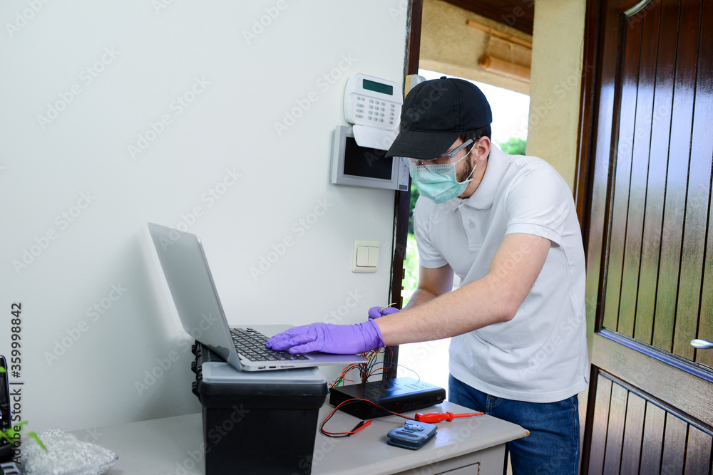 handsome young man telephone operator worker fixing internet issue connexion at client house with surgical mask and gloves during pandemic period handsome young man telephone operator worker fixing internet issue connexion at client house with surgical mask and gloves during pandemic period
