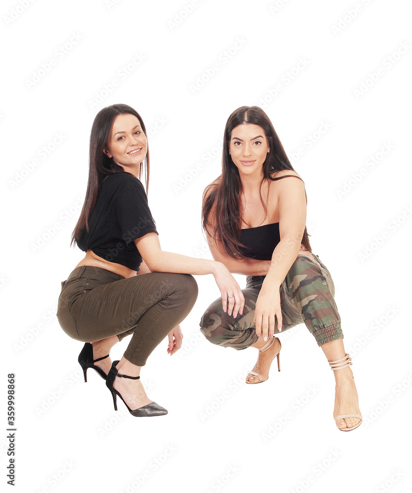 Two lovely woman crouching side by side in the studio Two lovely woman crouching side by side in the studio