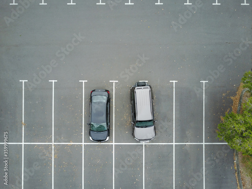 Aerial view of two cars in car park, one of which is over two spaces photo