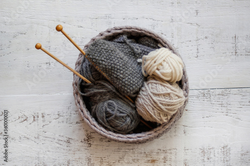 Knitting in grey woven basket with wooden knitting needles and grey and cream wool photo