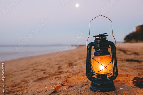 Close up of kerosene lamp on beach at dusk photo