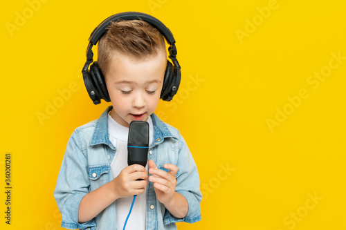 Portrait of singing little boy with headphones and microphone