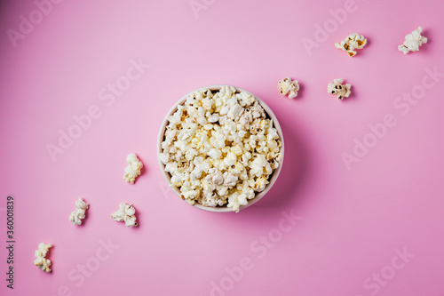 A pink bowl of popcorn on pink background, top view