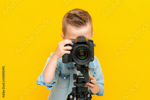 Adorable little kid taking a photo using a digital camera on a tripod