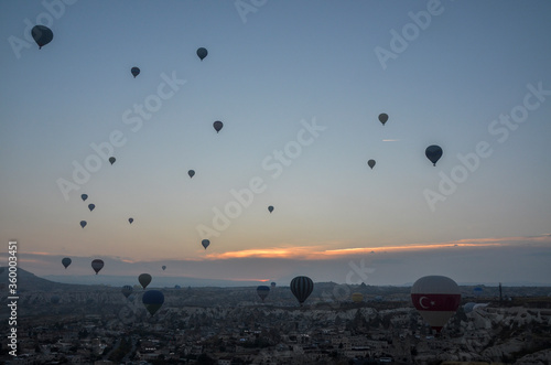 Colorful hot air balloons flying over the valley and rock formations with fairy chimneys near Goreme, Cappadocia, Turkey
