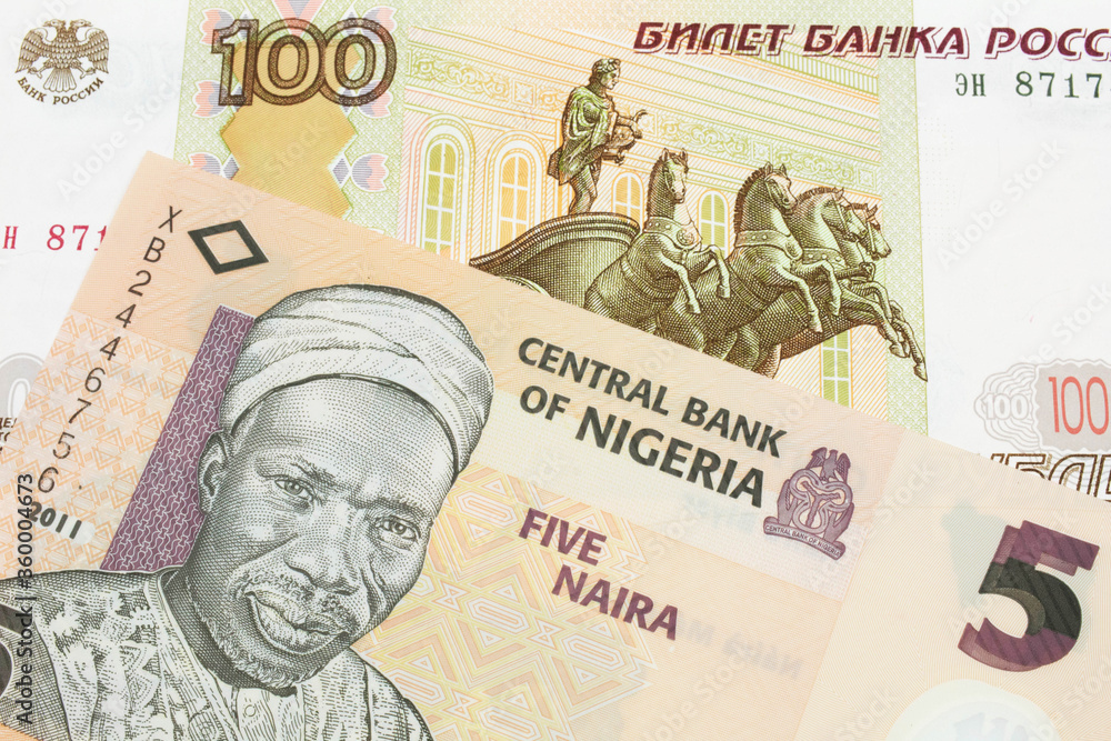 A macro image of a Russian one hundred ruble note paired up with a orange, plastic five naira note from Nigeria.  Shot close up in macro.