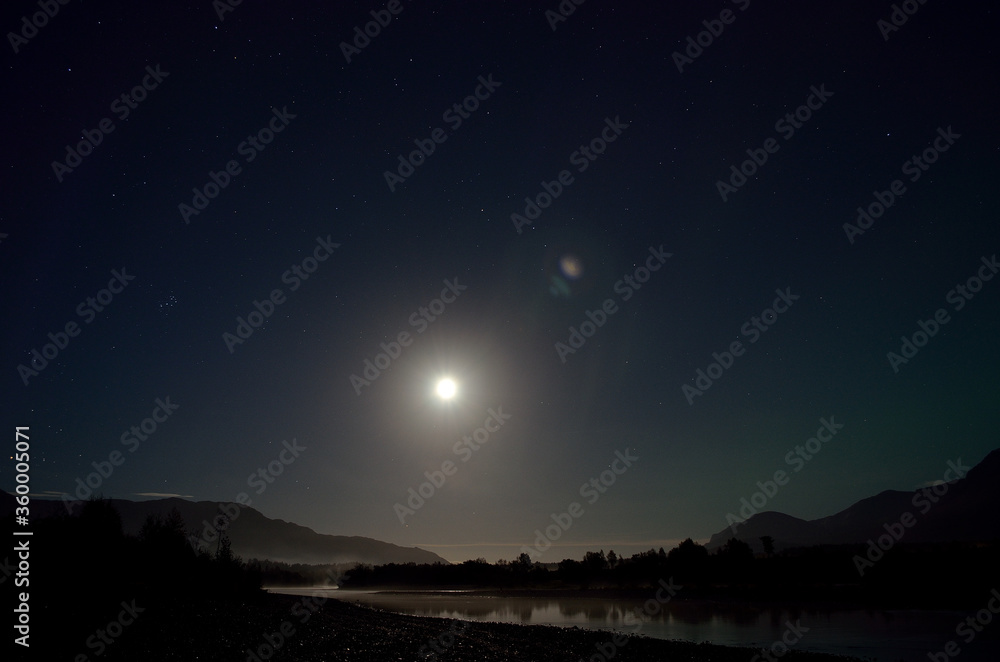 faded aurora borealis on full moon night as the moonlight reflected by the river surface faded aurora borealis on full moon night as the moonlight reflected by the river surface