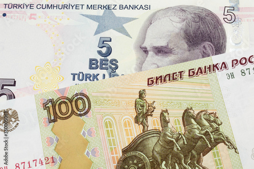 A macro image of a Russian one hundred ruble note paired up with a purple  five real bank note from Turkey.  Shot close up in macro.