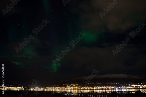 aurora borealis, northern lights over snowy mountain, reflective fjord water and whale island in northern norway in late autumn