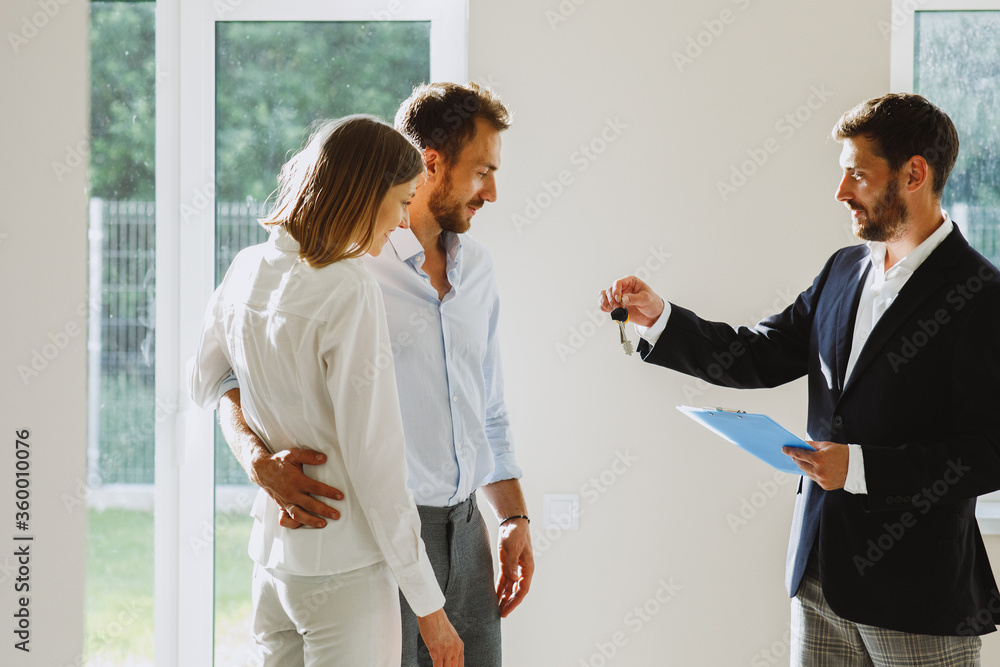 Real estate agent handing keys to young couple. Man and woman in new home Real estate agent handing keys to young couple. Man and woman in new home