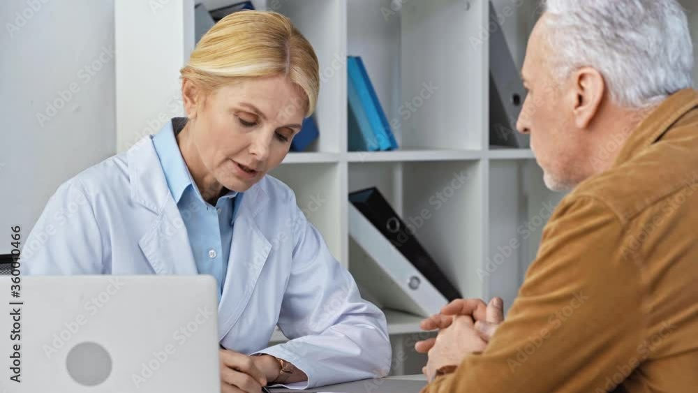 attractive mature doctor talking with man and writing prescription attractive mature doctor talking with man and writing prescription