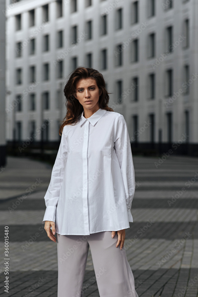fashion portrait of a girl in a gray sweater and white sheep on the background of modern architecture fashion portrait of a girl in a gray sweater and white sheep on the background of modern architecture