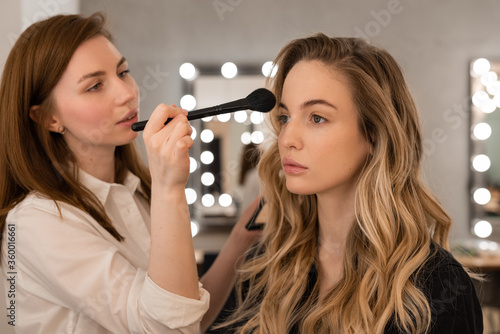 Makeup artist applying bronzer on model face photo