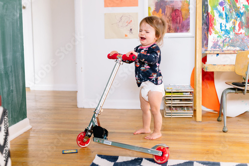 little girl cries trying to ride scooter photo