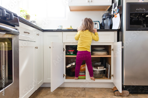 Little girl climbs on kitchen cabinet
