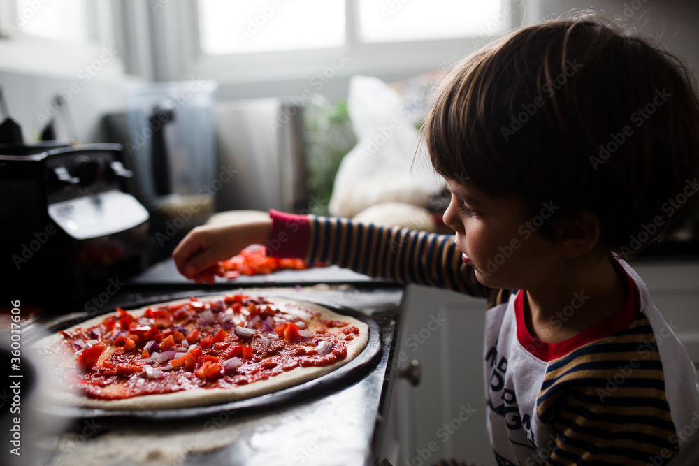 © Maria Manco/Stocksy - Boy makes home made pizza at home in the kitchen © Maria Manco/Stocksy - Boy makes home made pizza at home in the kitchen