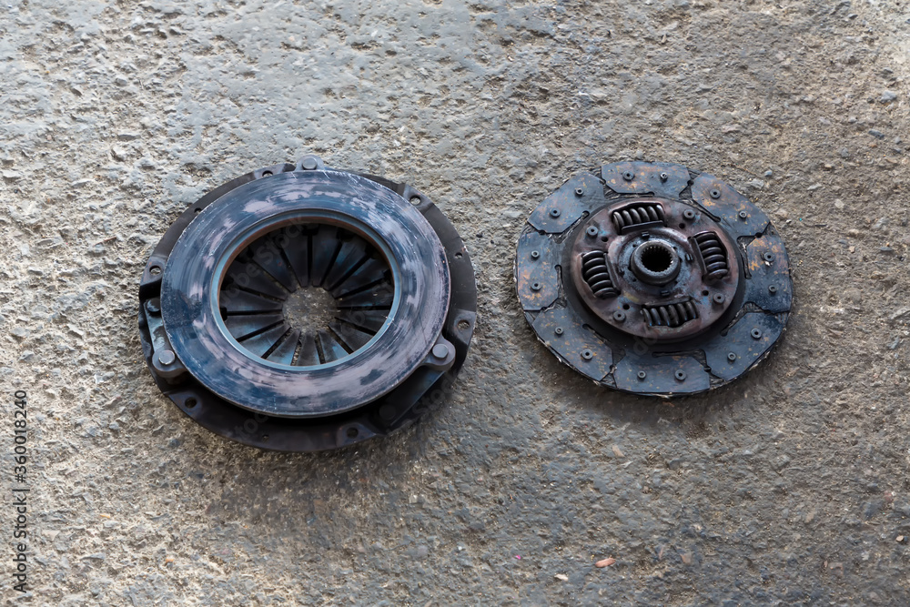 Old Disc Clutch and cover on floor. Old rusty clutch and the disc lies in the garage. Car rusty clutch pressure plate assembly  with clutch disc plate and fly wheel