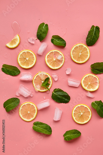 Fototapeta Naklejka Na Ścianę i Meble -  Composition with cut citrus fruits on pink background. Creative summer background composition with lemon slices, leaves mint and ice cubes. Minimal top down lemonade drink concept.Top view