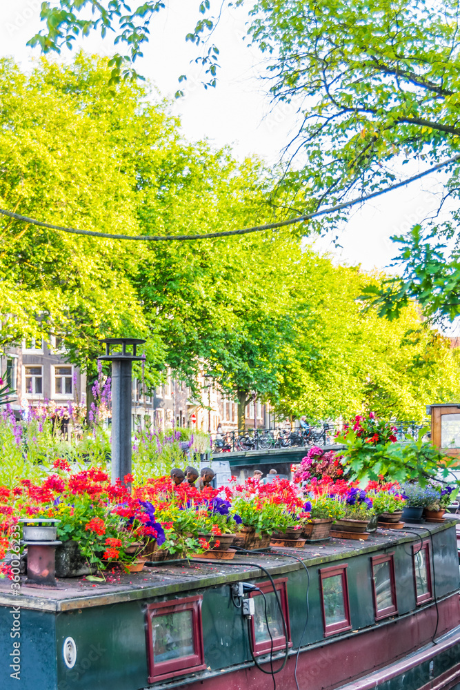Amsterdam, Netherlands - July 19, 2018: Colorful boathouse with lots of flowers on the canals of Amsterdam Amsterdam, Netherlands - July 19, 2018: Colorful boathouse with lots of flowers on the canals of Amsterdam