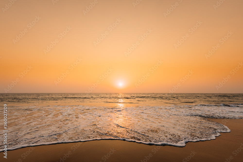 Sunset Sun Above Sea. Natural Sunrise Sky Warm Colors Over Ripple Sea. Ocean Water Foam Washing Sandy Beach At Sunset