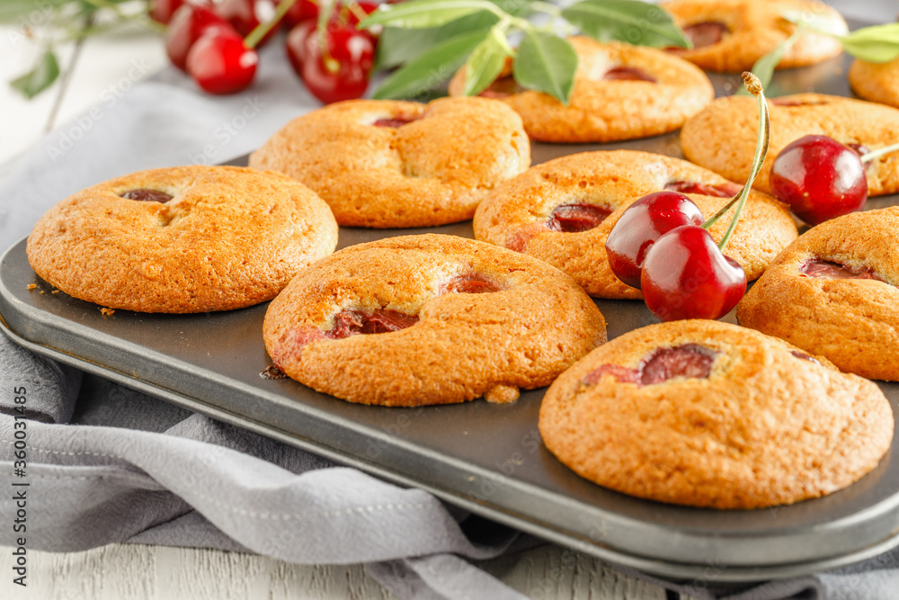 Homemade cherry muffins and fresh cherries on a light background. Delicious dessert