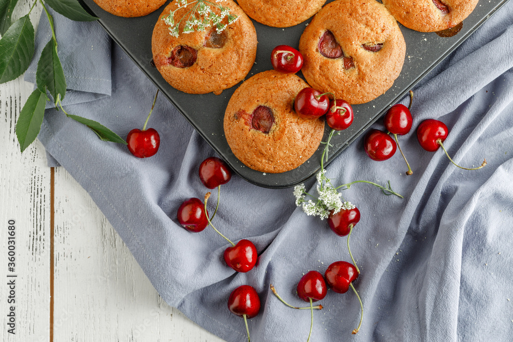 Fototapeta premium Homemade cherry muffins and fresh cherries on a light background. Delicious dessert