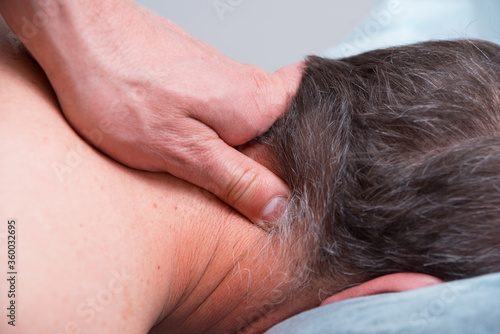 Physical therapist is making some deep massage on a mans neck.
