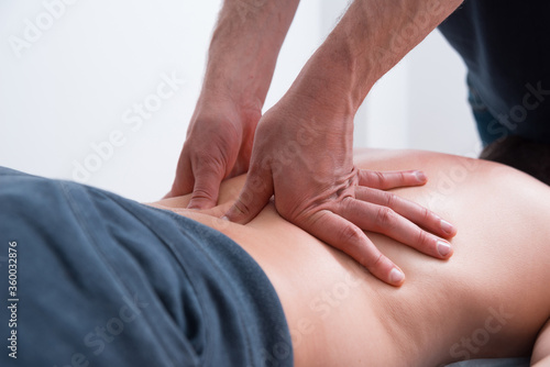Physical therapist pressing or pushing on lower back maknig deep massage.
