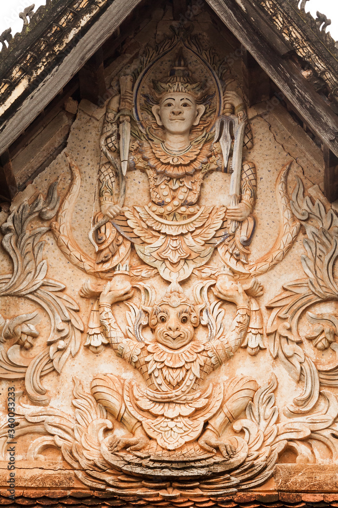 Laos. Carving of Hindu God Vishnu and his carrier Garuda the mythical eagle at temple front.