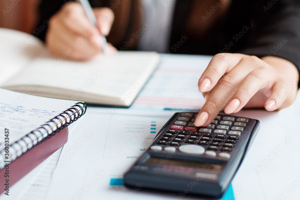 Businesswoman using a calculator to calculate the numbers Businesswoman using a calculator to calculate the numbers