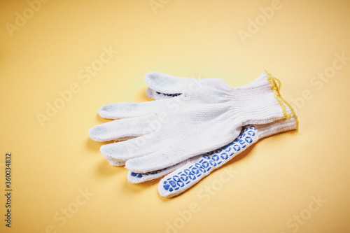 white textile gloves over yellow background with copy space. construction worker concept. handyman concept. © Andrii