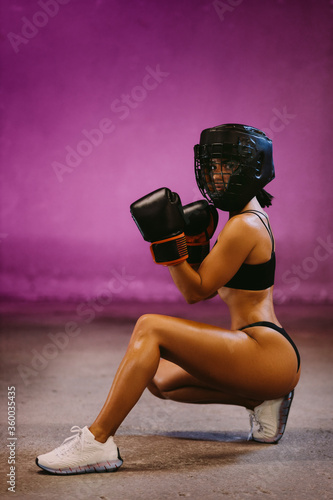 Платно beautiful woman fighter in boxing gloves posing in headgear indoors