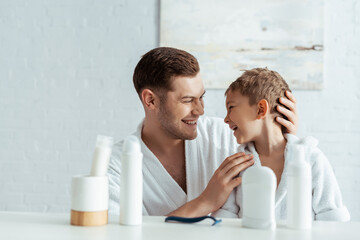 selective focus of happy father touching son near toiletries in bathroom