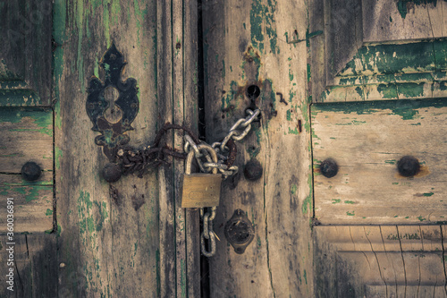 Texture of an old door closed with padlock and chain in a European architecture in the interior of Portugal