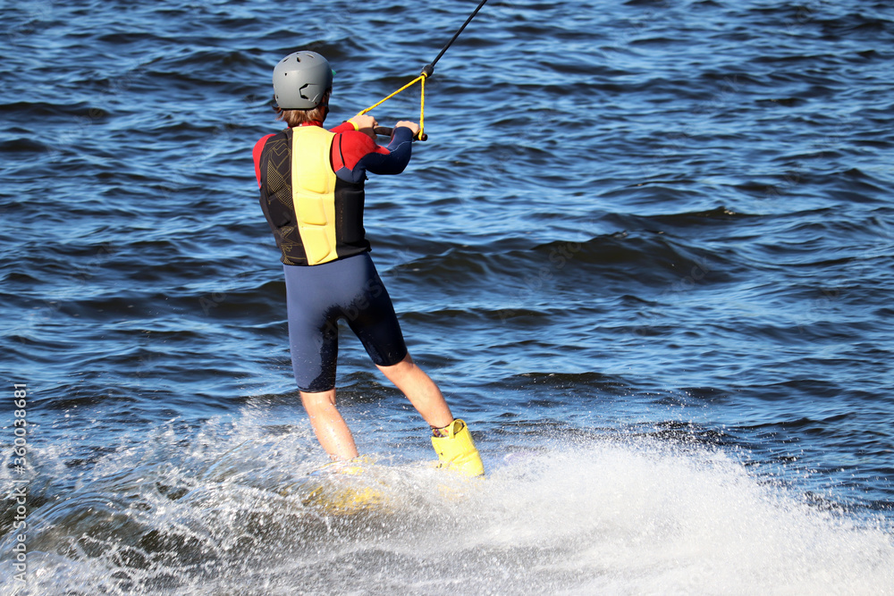 Wakeboarding in sunny day, man performs a trick in a spray of water. Surfer in the wake park, summer sport Wakeboarding in sunny day, man performs a trick in a spray of water. Surfer in the wake park, summer sport