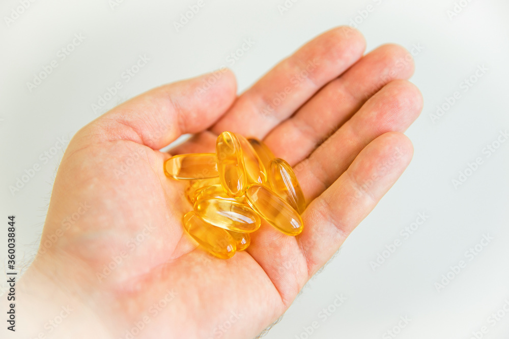 Yellow capsules of vitamin omega 3 in your hand. Biologically active additive. Fish oil in tablets. Medical support and treatment. Yellow capsules of vitamin omega 3 in your hand. Biologically active additive. Fish oil in tablets. Medical support and treatment.