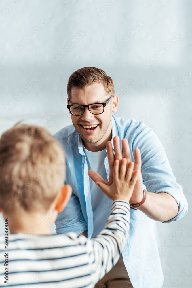 Φωτογραφία back view of boy giving high five to happy father
