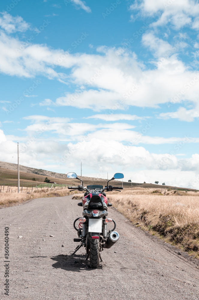 traveling the world with a motorcycle, parked in the countryside with a mountainous backdrop on a rural street