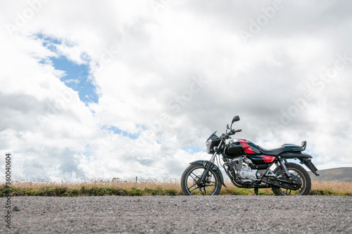 traveling the world with a motorcycle, parked in the countryside with the mountainous background