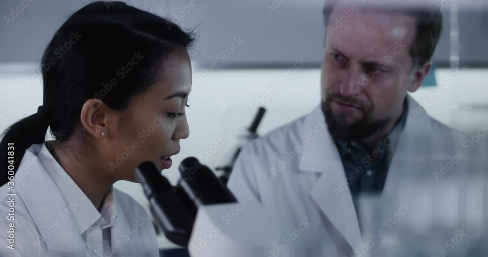 Scientists working in futuristic laboratory. Using microscope and discussing results Scientists working in futuristic laboratory. Using microscope and discussing results