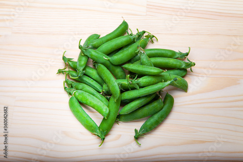 green peas in pods lies on a wooden background. Healthy green vegetables. Place for text