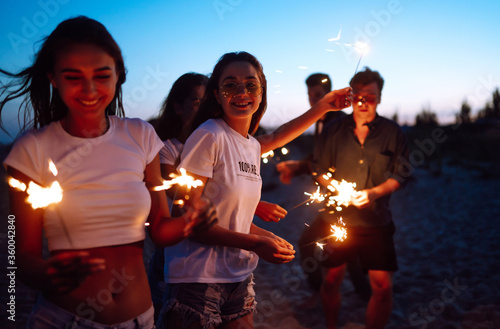 Photography Group of young people having fun with sparklers outdoors at the sea shore