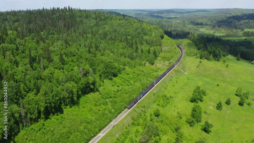 Drone view of agricultural green fields with lush woods and train on railroad in bright sunlight Drone view of agricultural green fields with lush woods and train on railroad in bright sunlight