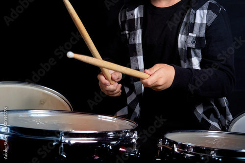 Close-up of the hands of a child who plays the drums.