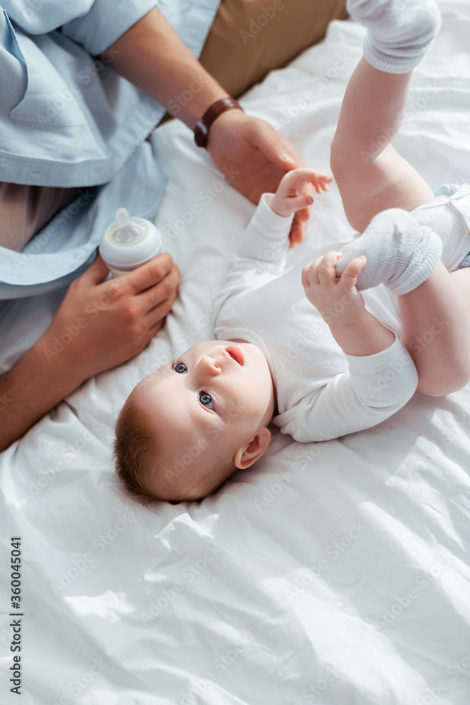cropped view of father holding baby bottle with milk near adorable little son cropped view of father holding baby bottle with milk near adorable little son