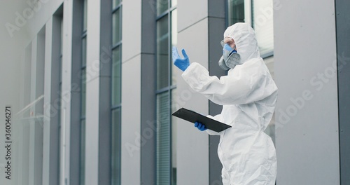 Wallpaper Mural Female office worker in mask going to work and man in white suit and respirator measuring her temperature, letting go. Allowing pass to business center for visitor. Covid-19 pandemic. Permit to enter. Torontodigital.ca