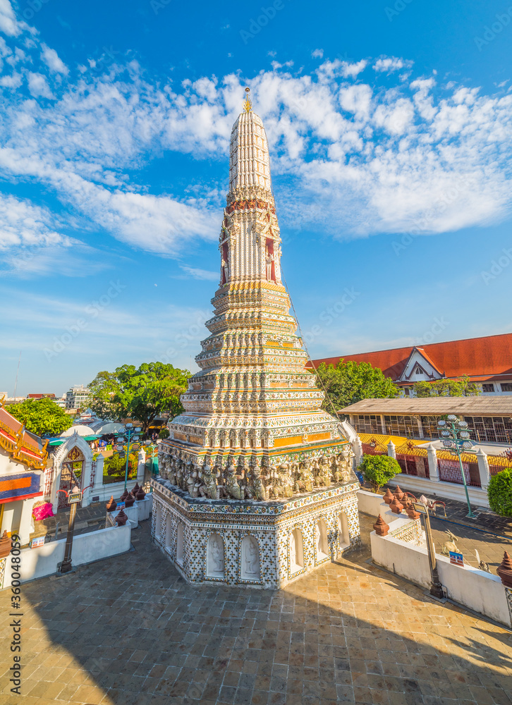 Naklejka premium White Ancient Pagoda At Wat Arun (Temple Of Dawn) With Blue Sky With Clouds. A Famous Place and Tourist Attraction In Bangkok, Thailand.