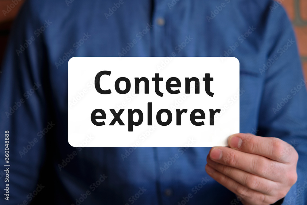 Content explorer text on a white sign in the hand of a man in a blue shirt Content explorer text on a white sign in the hand of a man in a blue shirt