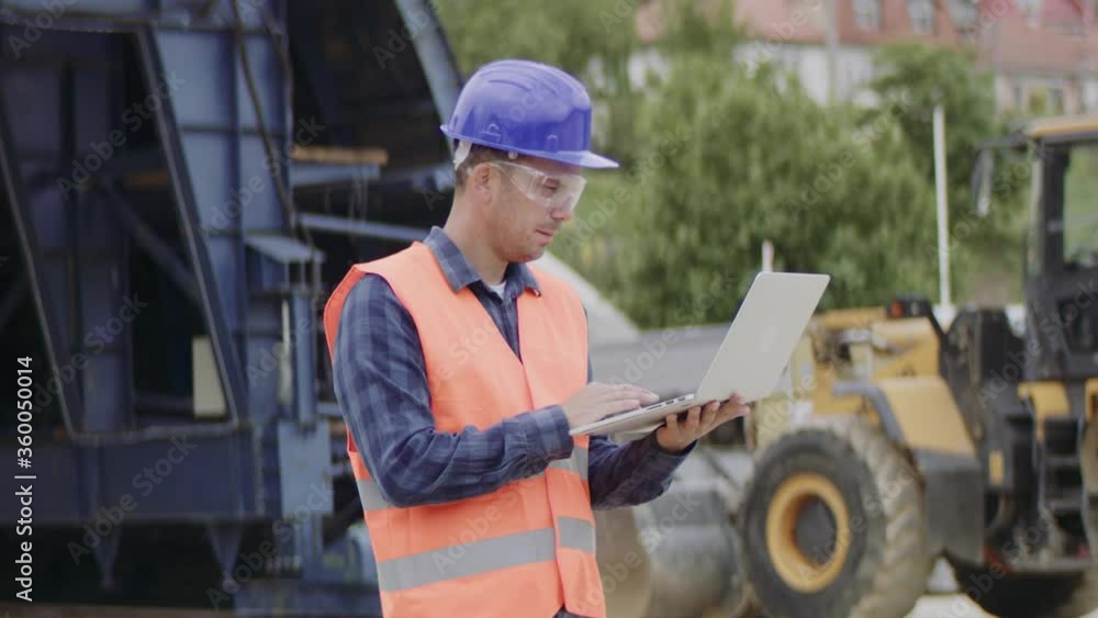 Construction engineer or a supervisor with a halmet and protective equipment on a building construction site using a laptop. Construction engineer or a supervisor with a halmet and protective equipment on a building construction site using a laptop.