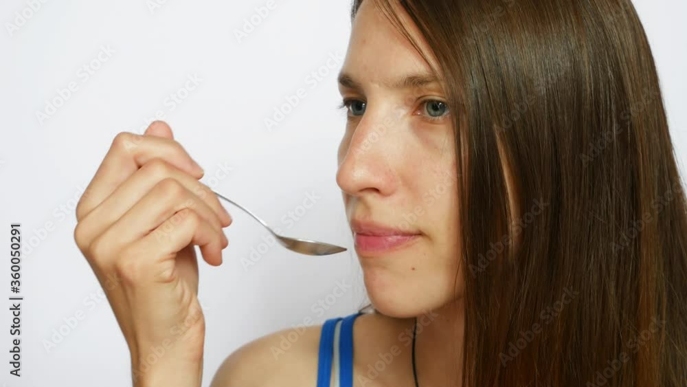 A beautiful lady eats yogurt with a spoon